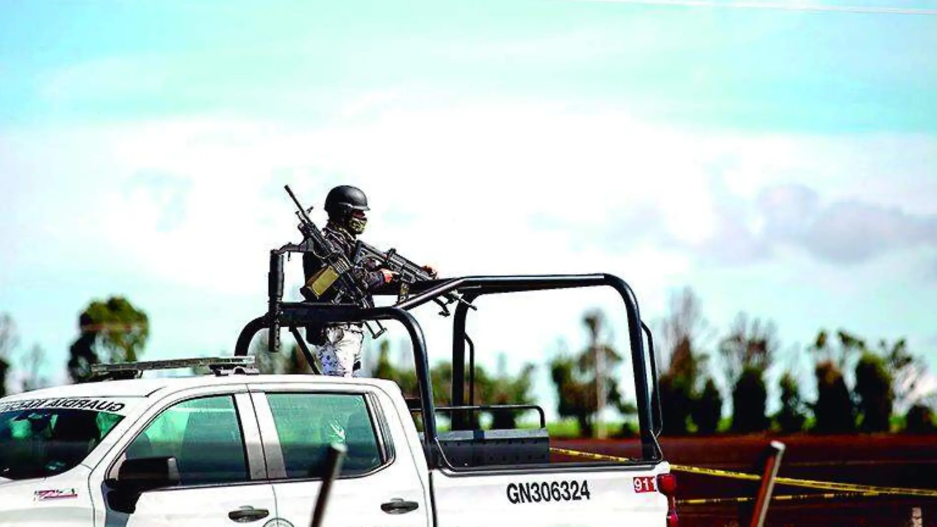 Elemento de la guardia nacional sobre una patrulla en una zona acordonada por la policía